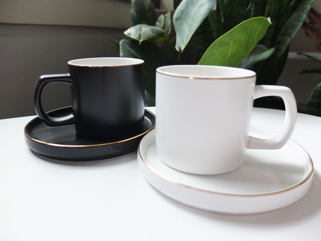 black and white mugs with gold rims and saucers